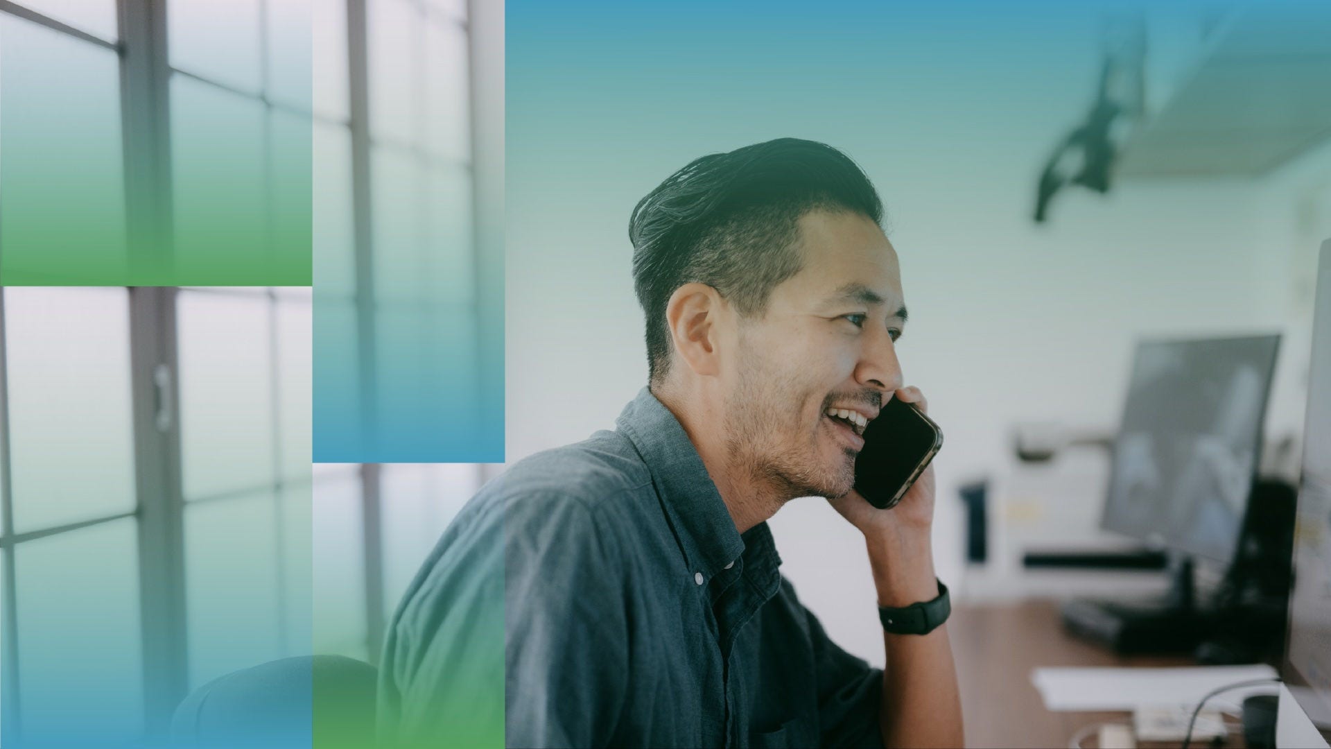 Person seated indoors, holding a smartphone to one ear while wearing a long-sleeve button-up shirt, with abstract green and blue translucent graphic shapes overlaid on the image and a softly lit office-style background.
